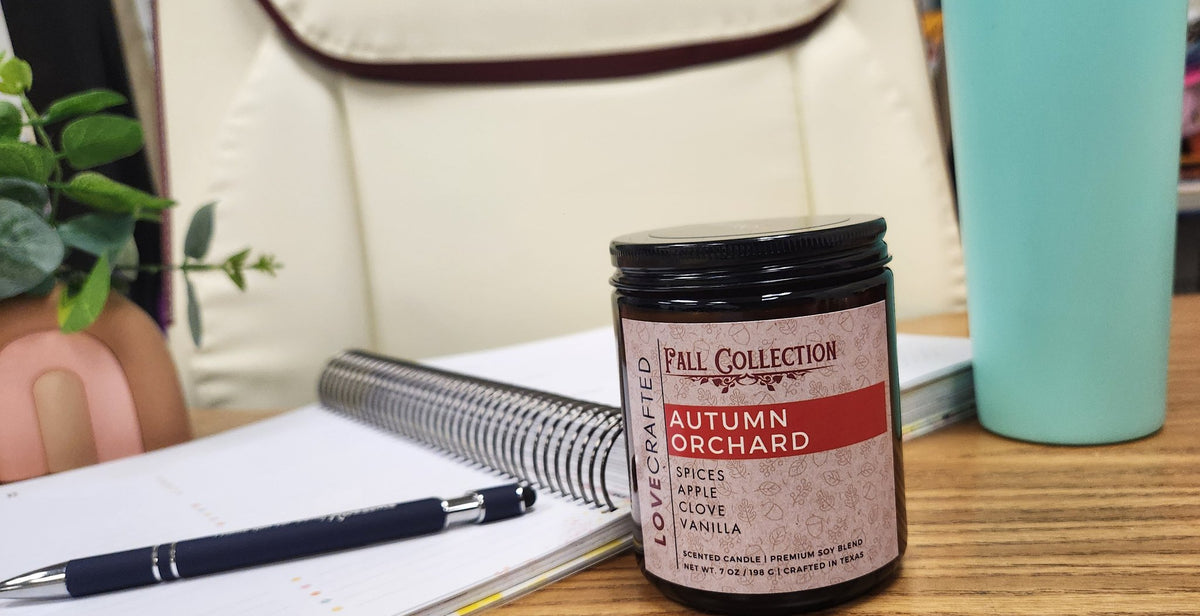 Autumn Orchard candle on a desk beside a notebook and pen