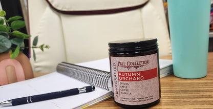 Autumn Orchard candle on a desk beside a notebook and pen