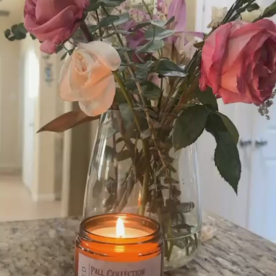 Video of a lit Honey Spiced Pear candle beside a vase of pink roses